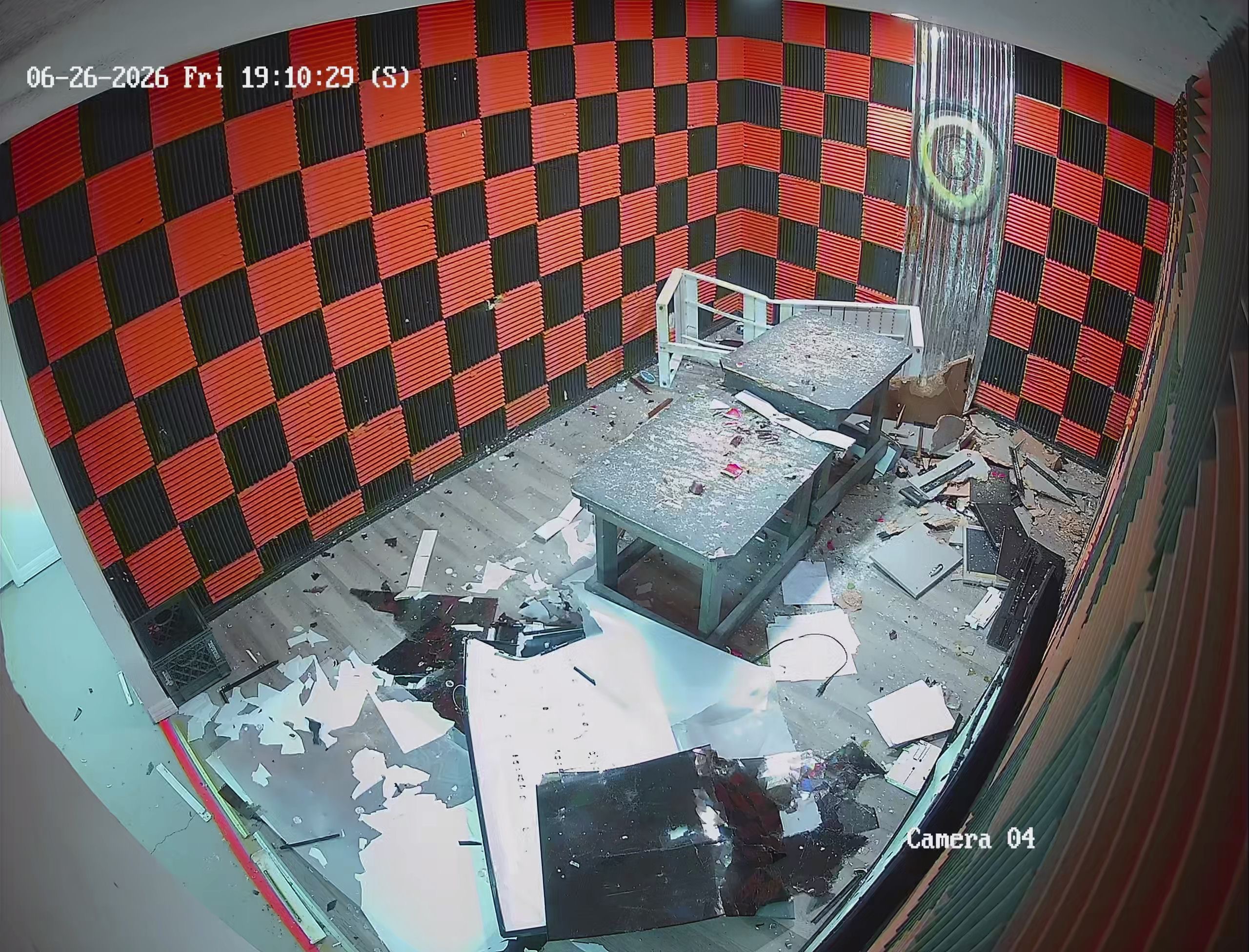 Security camera view of fully demolished Crash Out rage room after a session — shattered electronics and debris covering the floor